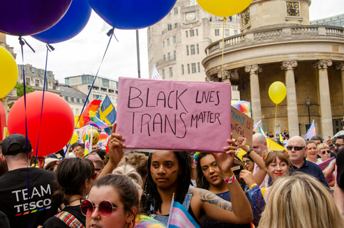 Viele Menschen bei einer Demonstration. Eine Person hält ein Schild, auf dem „BLACK TRANS LIVES MATTER“ steht.