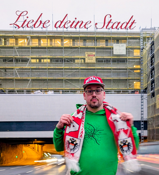 Sean Köllewood mit Colonia-Schal vor dem Schriftzug „Liebe deine Stadt“ an der Nord-Süd-Fahrt in Köln (Foto: Ümit Sönmez)