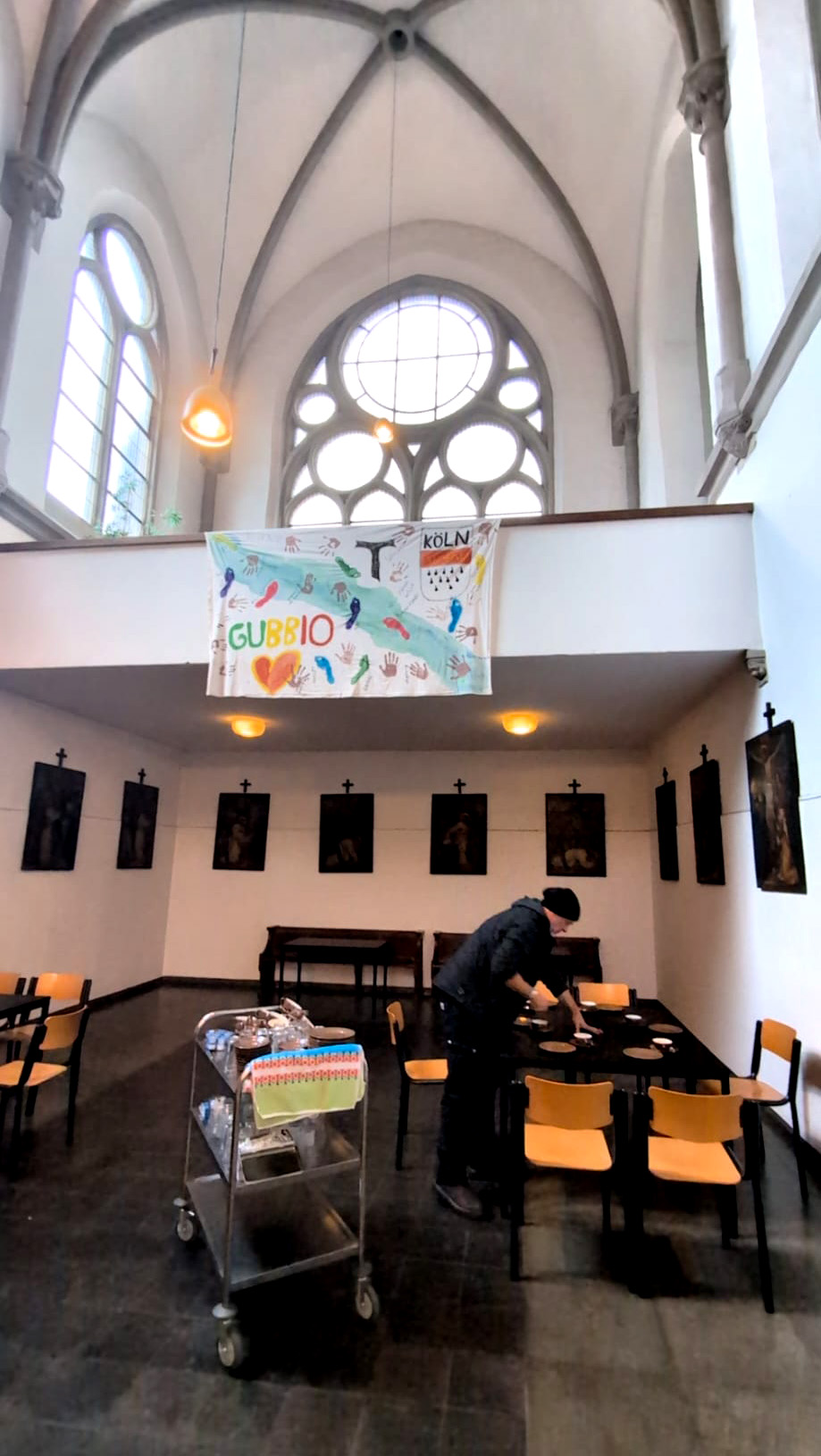 Raum in der Kirche, ein Mensch verteilt Geschirr auf Tischen
