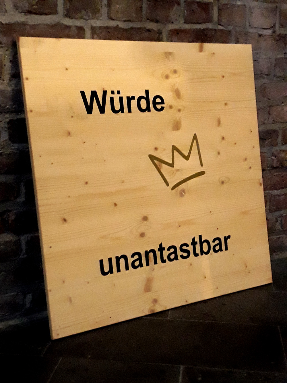 Holzschild mit einer Krone und den Worten Würde unantastbar